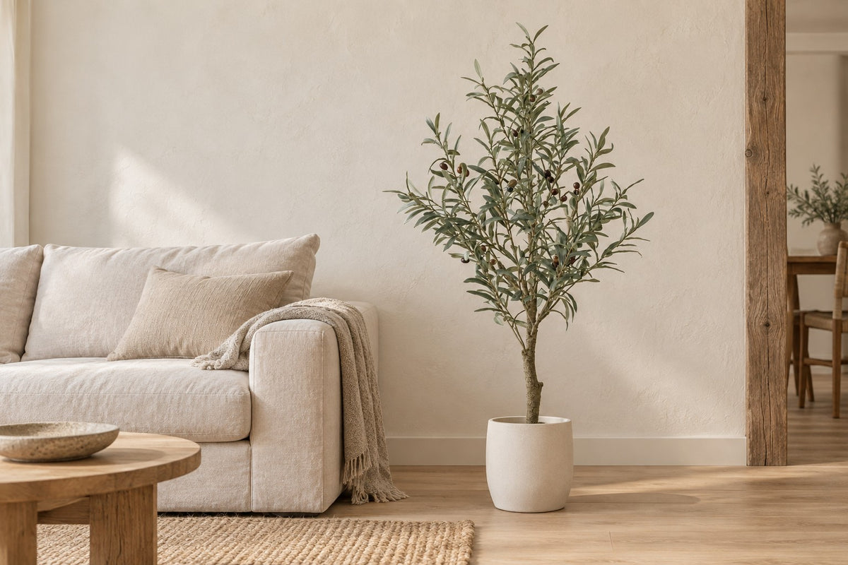 Kunstigt oliventræ, 117 cm, i a white ceramic planter i en lys stue